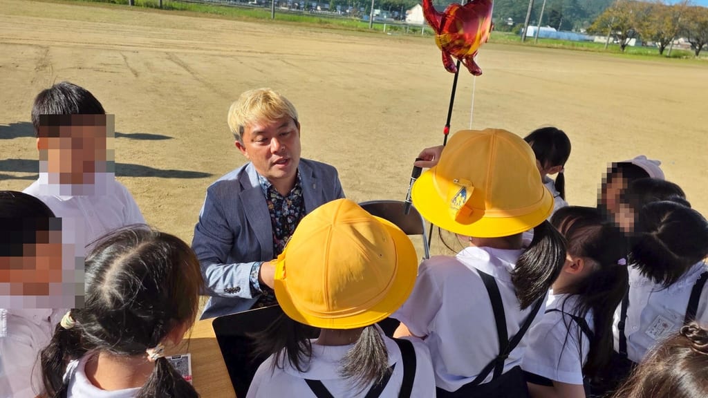 マジック教室のテーブルで、黄色い帽子の子どもたちに話しかけるコンプレッサー