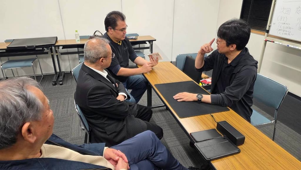まじっぱで、テーブルを囲み、身ぶりを交えて話すメンバーたち