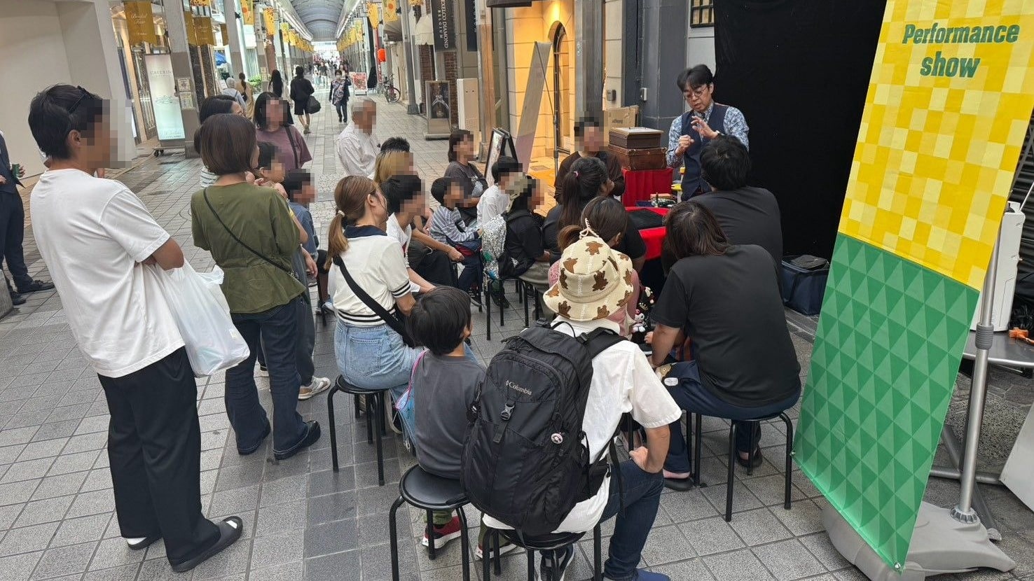 スゴ技ストリートで、富山市総曲輪通りのアーケードに並べた椅子のお客さまにマジックを見せるマーサ