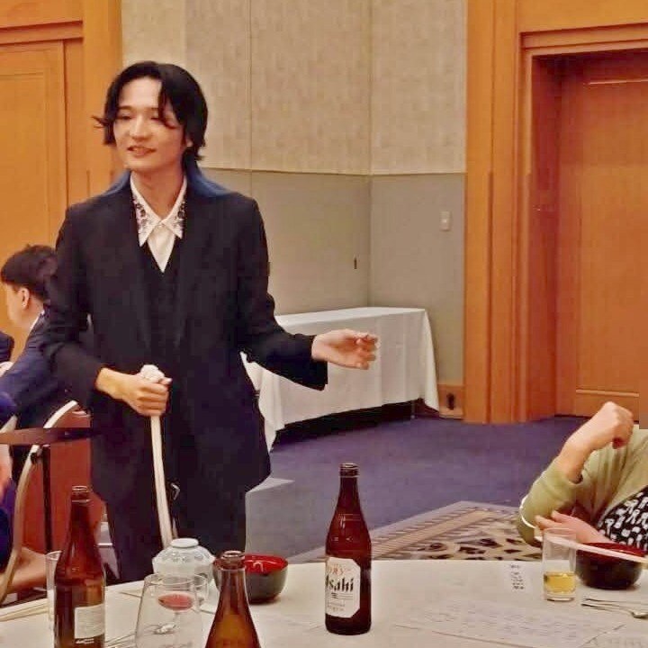 懇親会の円卓のそばで、白いロープを手にお客さまへ話しかける所属マジシャンのよぉすけ